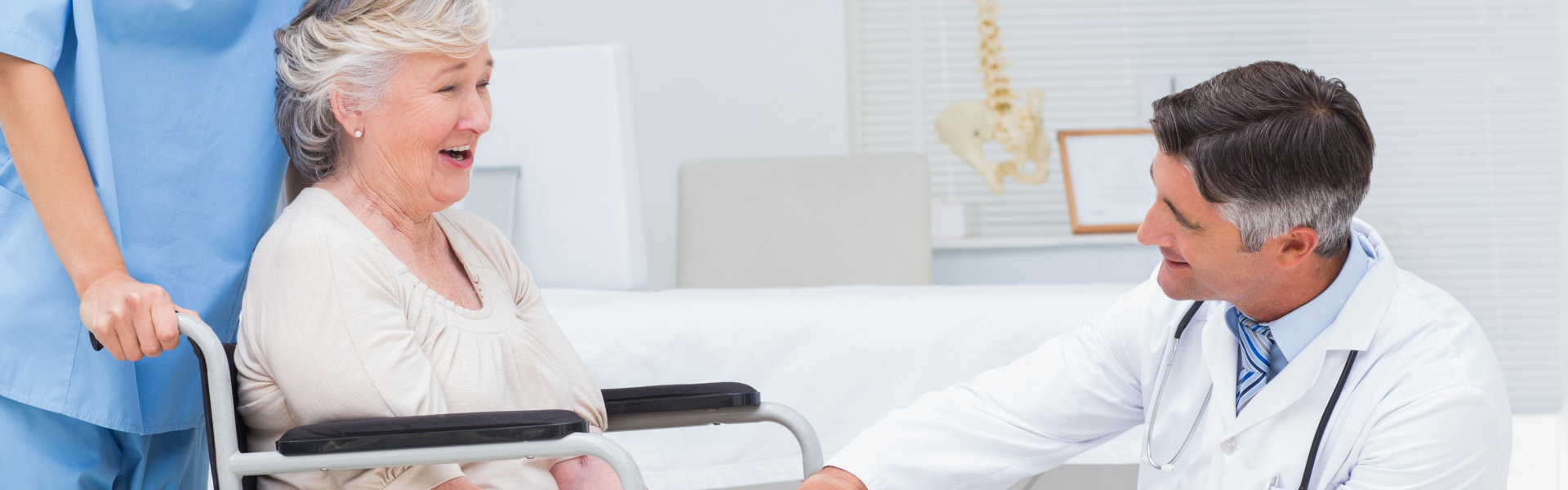 Male orthopedic doctor examining senior womans knee in clinic